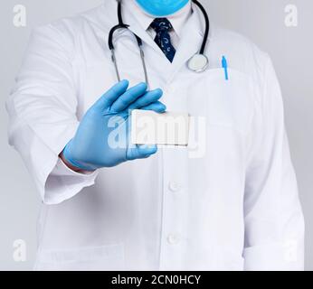 Der Erwachsene Arzt ist in einer weißen Robe Uniform gekleidet Und blaue sterile Handschuhe stehen und ho Stockfoto