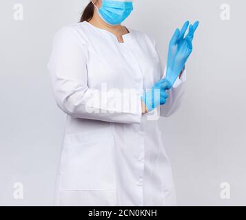 Arzt in einem weißen Mantel und Maske zieht an Medizinische Hände Latexhandschuhe vor den Verfahren Stockfoto