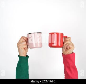 Zwei Hände mit Keramikbechern auf weißem Hintergrund Stockfoto