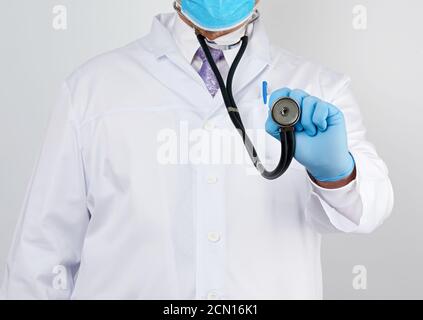 Doktor in einem weißen Mantel und Krawatte hält in seinem Hand ein schwarzes Phonendoskop Stockfoto