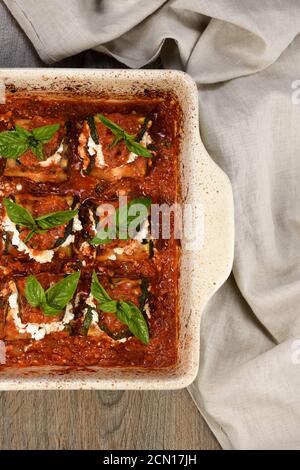 Gebackene Zucchini Brötchen gefüllt mit Ricotta und Basilikum unter Tomaten - Zwiebel - Sauce in einer Pfanne Möhre Stockfoto