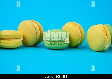 Mehrfarbige runde gebackene Macarons Kuchen auf hellblauem Hintergrund, Dessert steht in einer Reihe Stockfoto