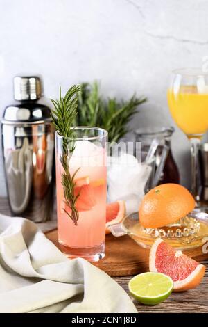 Gin-Cocktail mit Rosmarin und Granatapfel auf einem Tisch mit Zitrusfrüchten und Getränken. Stockfoto