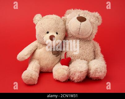 Zwei beigefarbene Teddybären sitzen zusammen gedrängt Stockfoto