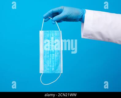 Arzt in blauem Latex sterile Handschuhe hält eine blaue Einweg Maske aus Vlies Stockfoto