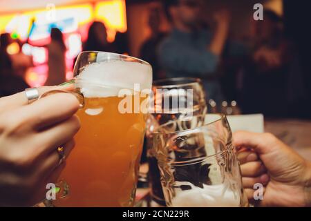 Nahaufnahme einer Gruppe von Menschen klirren Gläser mit Bier vor Bokeh Hintergrund. Ältere Menschen Hände. Stockfoto