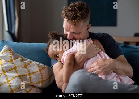 Ein Vater kuschelt seine schläfrige Tochter Stockfoto