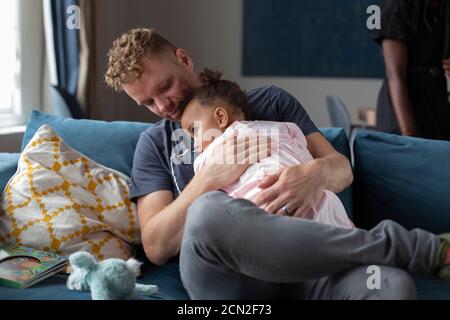 Ein Vater hält seine junge Tochter auf der Couch Stockfoto