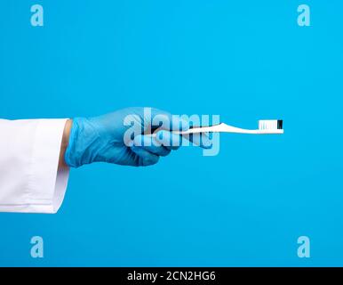 Arzt Therapeut ist in einer weißen Robe Uniform gekleidet und Blaue sterile Handschuhe mit einer Zahnbürste Stockfoto