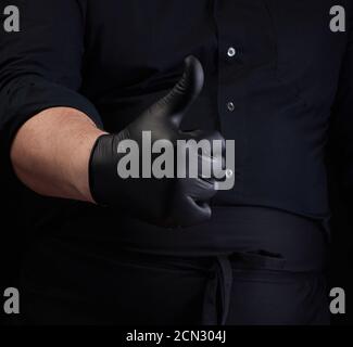 Männlicher Koch in schwarzer Uniform und schwarze Latexhandschuhe zeigt Wie Geste der Genehmigung Stockfoto