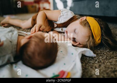 Vorschule Mädchen schlafen auf dem Boden mit Baby und saugen an Ein Beruhigungssauger Stockfoto