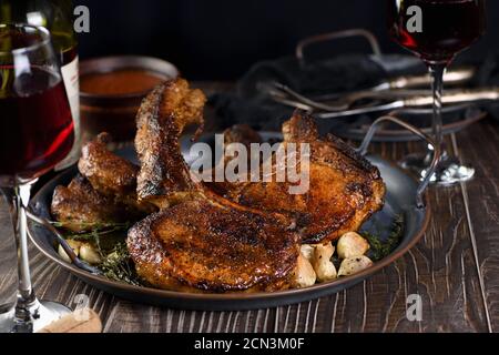 Saftiges, gebratenes Schweinehüsch auf einem Knochen in Öl mit Knoblauch und Kräutern in einer Pfanne. Nahaufnahme. Stockfoto