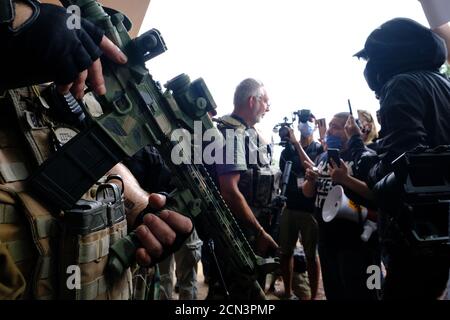 Stone Mountain, GA, USA. August 2020. Mitglieder einer Gruppe namens iii% Security Force stellen sich mit Demonstranten. Stockfoto