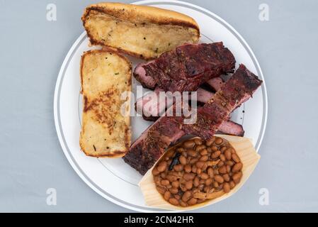 Blick von oben auf das Essen mit halben Rippchen, gebackenen Bohnen und Butter geröstetes Brot wird so lecker schmecken, wie es aussieht. Stockfoto