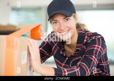 Junge Frau Verpackung und Klebeband Kartons Stockfoto