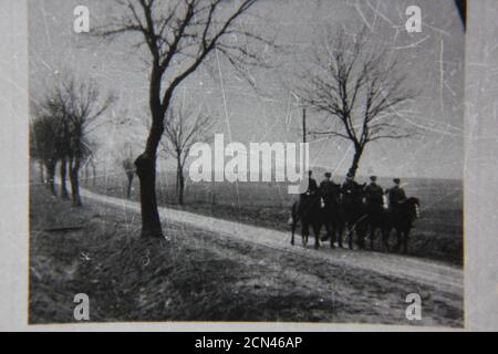 Feine Schwarz-Weiß-Fotografie aus den 1970er Jahren von fünf Männern auf Pferden, die einen Landweg hinuntertraben. Stockfoto