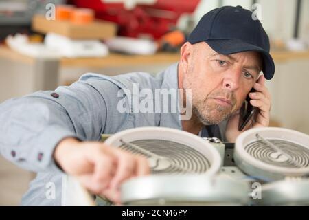 Klempner am Telefon Reparatur Wasserhahn in der Küche Stockfoto