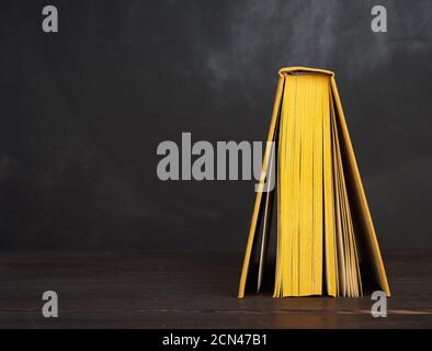 Buch in gelbem Hardcover gegen eine schwarze Kreidetafel öffnen Stockfoto