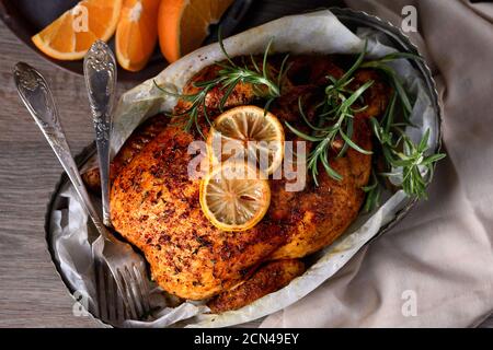 Gebackenes Hähnchen in Gewürzen mit knusprig appetitlich gebratener Kruste in einem Tablett, dunkel launisch Stockfoto