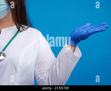 Ärztin in einem weißen Mantel, blauen Latexhandschuhen und einer Schutzmaske auf seinem Gesicht bedingt halten Stockfoto