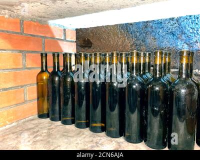 Mockup Bild von Rotweinflaschen auf Stein Regal in lokalen Weingut - hausgemachter Wein oder verschiedene Alkohol Fruchtgetränke in lokalen Weinladen. Essen und Trinken Stockfoto