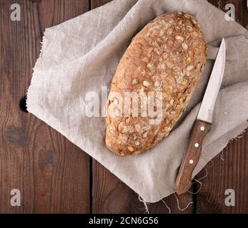 Gebackenes ovales Brot aus Roggenmehl mit Kürbiskernen Auf einer grauen Leinenserviette Stockfoto