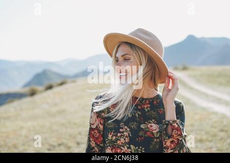 Schöne lächelnde blone junge Frau Reisende in Kleid und Filz Hut auf der Straße, Reise in die Berge, Altai Stockfoto