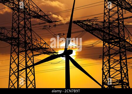 Zwei Freileitungsmasten und eine Windturbine vor der Sonne, Witten, Deutschland, Europa Stockfoto