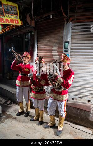 Drei indische Hochzeitsband-Musiker üben ihre tägliche Musikroutine am Abend auf der Straße in Kalkutta, Indien. Stockfoto