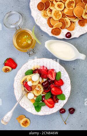 Porridge von winzigen Pfannkuchen mit Beeren, Sahne und Honig. Stockfoto
