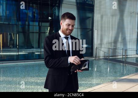 Geschäftsmann, der Geld in Wallet zählt. Geldkonzept, Geschäftsmann Freelance. Brieftasche in den Händen. Stockfoto