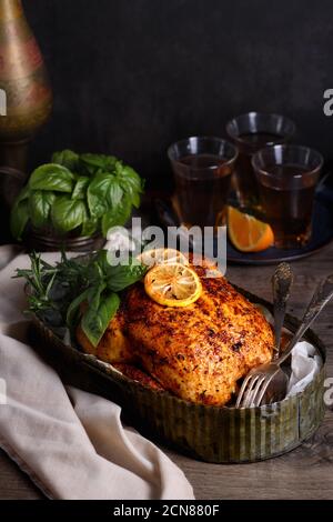 Gebackenes Hähnchen in Gewürzen mit knusprig appetitlich gebratener Kruste in einem Tablett, dunkel launisch Stockfoto