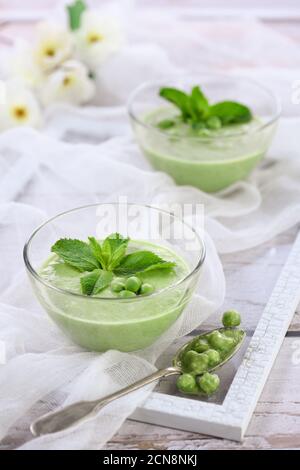 Gekühlte Suppe aus grünem Erbsenpüree mit zarter Milchcreme und erfrischender Minze Stockfoto