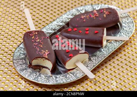 Hausgemachtes Eis auf einem Stock in dunkler Schokoladeneisung. Stockfoto
