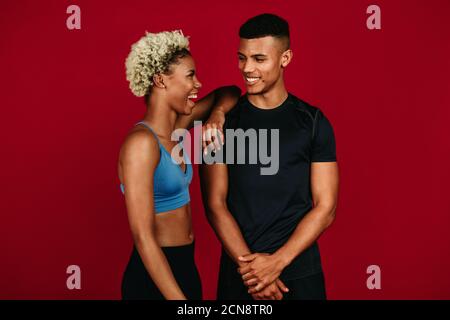 Fitnesspaar, das sich nach dem Training entspannt. Porträt eines afroamerikanischen Fitness-Paares, das lacht und miteinander redet. Stockfoto
