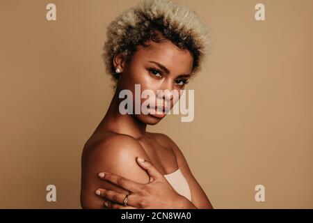 Seitenansicht Nahaufnahme einer afroamerikanischen Frau auf braunem Hintergrund. Porträt einer Frau mit lockigen braunen Haaren. Stockfoto