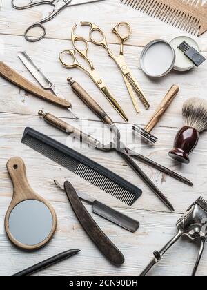 Klassische Pflege- und Friseurwerkzeuge auf Holzhintergrund. Draufsicht auf Barbershop Instrumente auf weißem Holztisch. Stockfoto