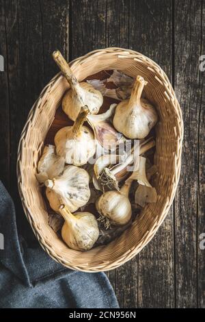 Weiße Knoblauchzwiebeln im Korb auf altem Holztisch und Serviette. Draufsicht. Stockfoto