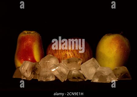 Foto von drei roten und grünen Apfel mit Eis in Wassertropfen auf schwarzem Hintergrund in Nahaufnahme Stockfoto
