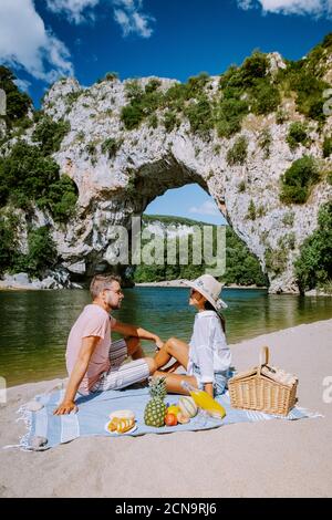 Paar am Strand am Fluss in der Ardeche Frankreich Pont d Arc, Ardeche Frankreich, Blick auf den Narural Bogen in Vallon Pont d'Arc in EINEM Stockfoto