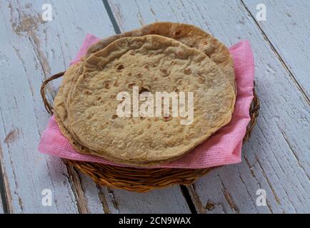 Indisches Fladenbrot chapatis serviert auf einem rosa Tuch und ein Weidenschale Stockfoto