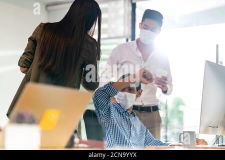 Büroangestellte tragen Gesichtsmaske Ellenbogen Begrüßung in neuen normalen Büroleben Stockfoto
