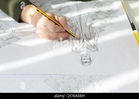 Modedesigner Hand skizzieren ein Haute Couture Hochzeitskleid mit einem Bleistift auf Zeichenpapier. Stockfoto