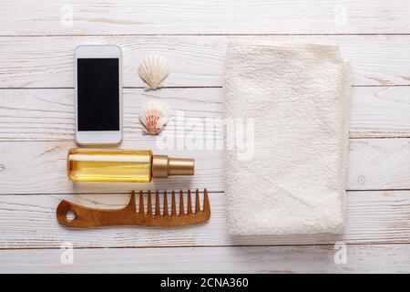 Sea accessories on wooden background Suntan oil, comb, towel, seashells, sunglasses. Top view Stockfoto