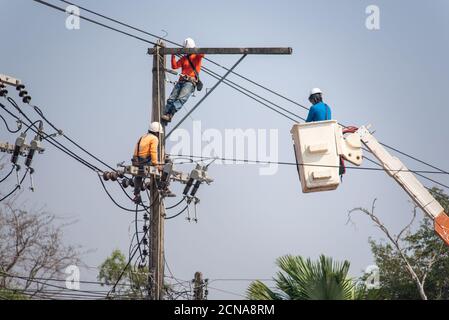 Elektriker klettern auf elektrische Pole zu installieren und zu reparieren Stromleitung an heißen Tagen. Stockfoto
