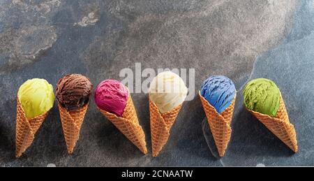 Set aus verschiedenen bunten Eis in Waffelkegel auf dem grauen Hintergrund. Lay-out-Ansicht. Stockfoto