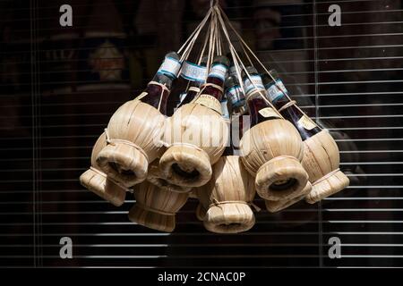 Ein Bündel von Flaschen Bardolino Wein, die vor einem Geschäft in Verona, Venetien, Italien, Europa hängen. Stockfoto