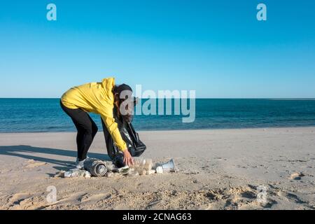 Frau nimmt Müll und Kunststoffe auf und säubert den Strand mit einer Mülltüte. Umweltaktivisten gegen den Klimawandel und die Umweltverschmutzung o Stockfoto