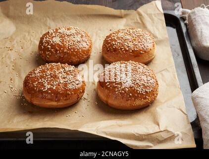 Gebackene Sesambrötchen auf braunem Pergamentpapier, Zutat für einen Hamburger Stockfoto