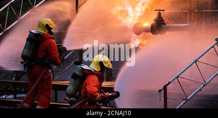 Panorama Feuerwehrmann Team mit Wassernebel Sprühen Feuer aus Explosion in der Ölplattform Stockfoto